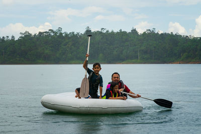 People in boat on lake against sky