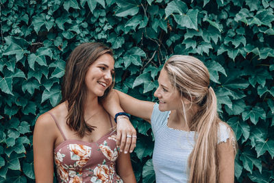 Smiling young friends standing against plants