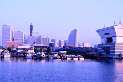 Modern buildings by river against sky in city