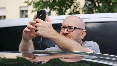 Man using mobile phone while standing by car