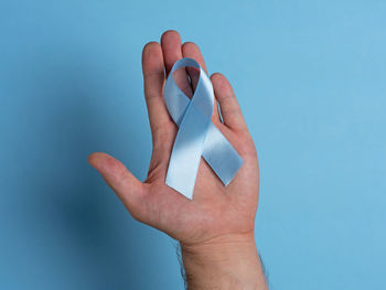 Close-up of human hand against blue background