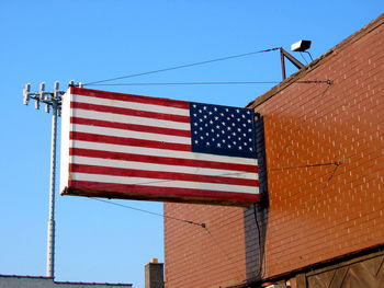 Low angle view of american flag attached to building against clear blue sky