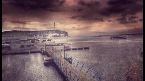 Pier on sea against cloudy sky