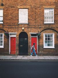 Woman walking on footpath against building