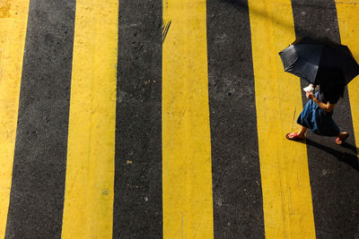 High angle view of woman walking on zebra crossing