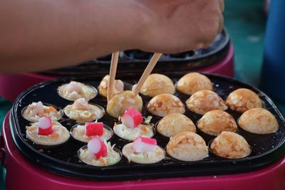 Cropped hand of person holding takoyaki with chopsticks