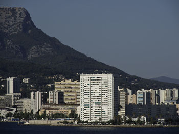 Buildings by sea against clear sky