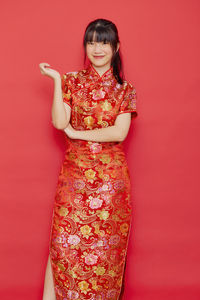 Portrait of a smiling young woman against red background