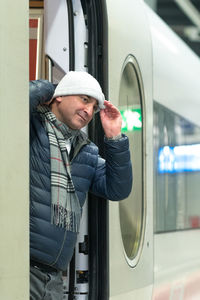 Man wearing knit hat while standing at train entrance