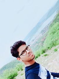 Portrait of young man in mountains against sky