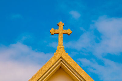 Low angle view of cross against building against sky