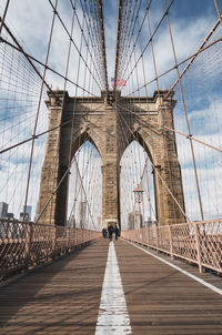 Low angle view of suspension bridge against cloudy sky