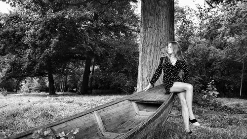 Young woman sitting on tree trunk in park