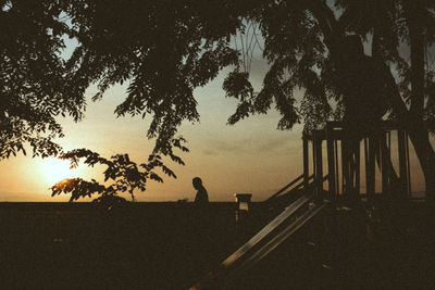 Silhouette man standing by tree on beach against sky