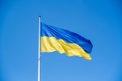 Ukrainian flag in the wind on blue sky background. large national yellow blue flag of ukraine. big