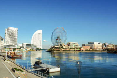 View of ferris wheel and buildings against clear blue sky