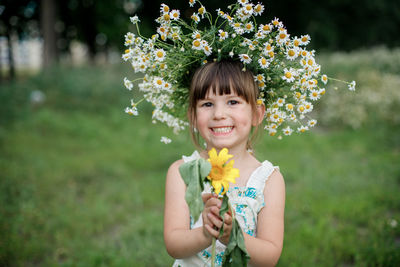 Portrait of smiling girl holding flowering plant