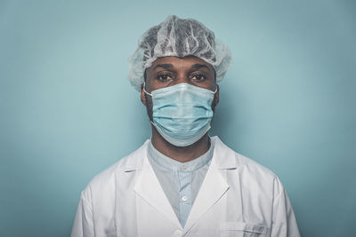 Close-up portrait of doctor against colored background