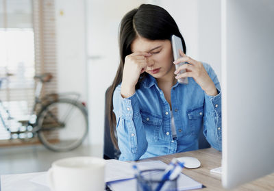 Young woman using phone while sitting on table
