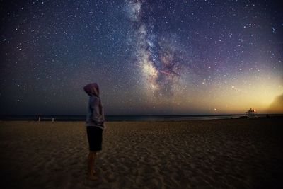 Woman standing on beach against sky at night