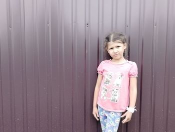 Portrait of girl standing against pink wall