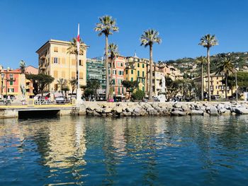 Sailboats in city by buildings against clear sky