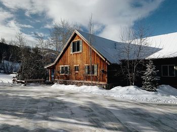 Snow covered houses by building against sky