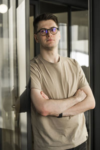 Portrait of young man standing against window