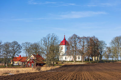 Traditional building by trees against blue sky