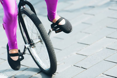 Low section of woman riding bicycle on street