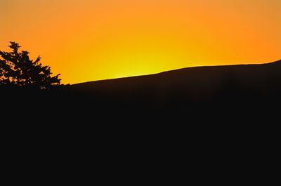 Scenic view of silhouette landscape against orange sky