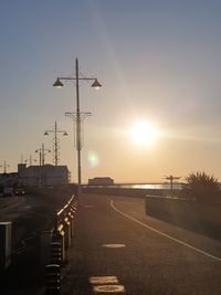 Street lights on road against sky during sunset