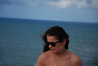 Side view of young man looking at sea against sky