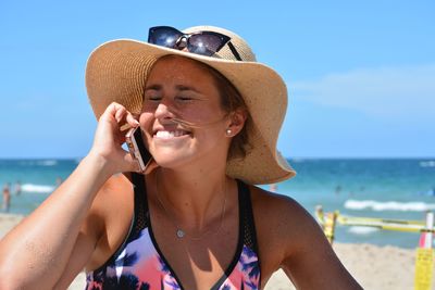 Smiling young woman using mobile phone at beach