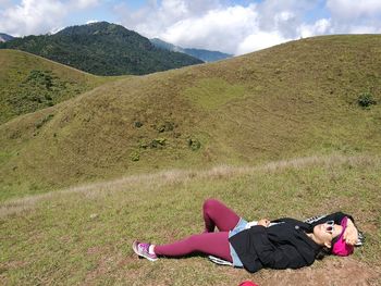 Woman lying on mountain against sky