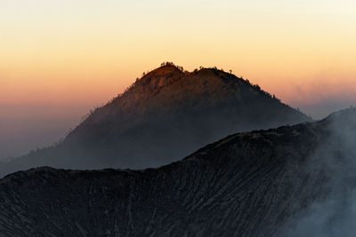 Scenic view of volcanic mountain against sky during sunset