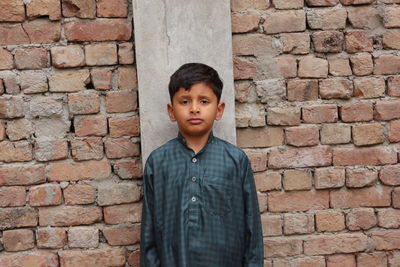 Portrait of child standing against brick wall