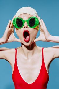 Portrait of young woman wearing sunglasses against blue background