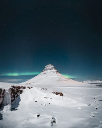 Scenic view of snowcapped mountain against sky at night