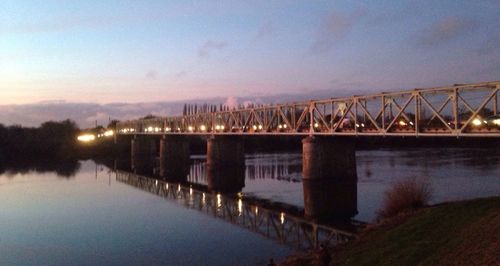 Illuminated bridge over river at night