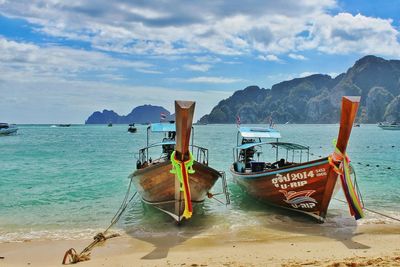 Longtail boats moored on shore against sky