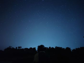 Rear view of silhouette man against sky at night