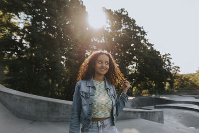 Smiling teenage girl looking at skate park looking away