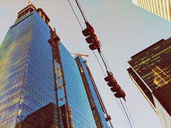 Low angle view of crane by building against sky