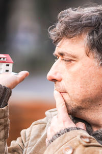 Close-up of man holding model house in city