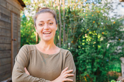 Portrait of smiling woman standing against tree