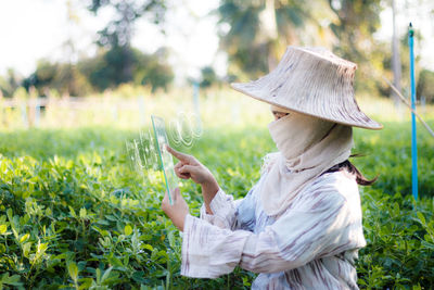 Side view of woman holding umbrella on field