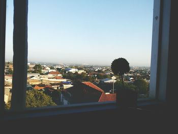 Buildings against clear sky seen through glass window