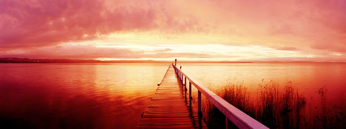 Pier over sea against sky during sunset