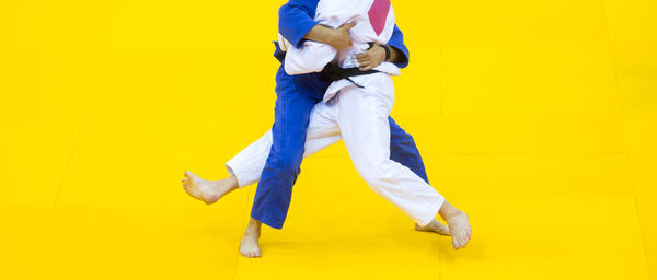 Low section of people practicing martial arts against yellow background